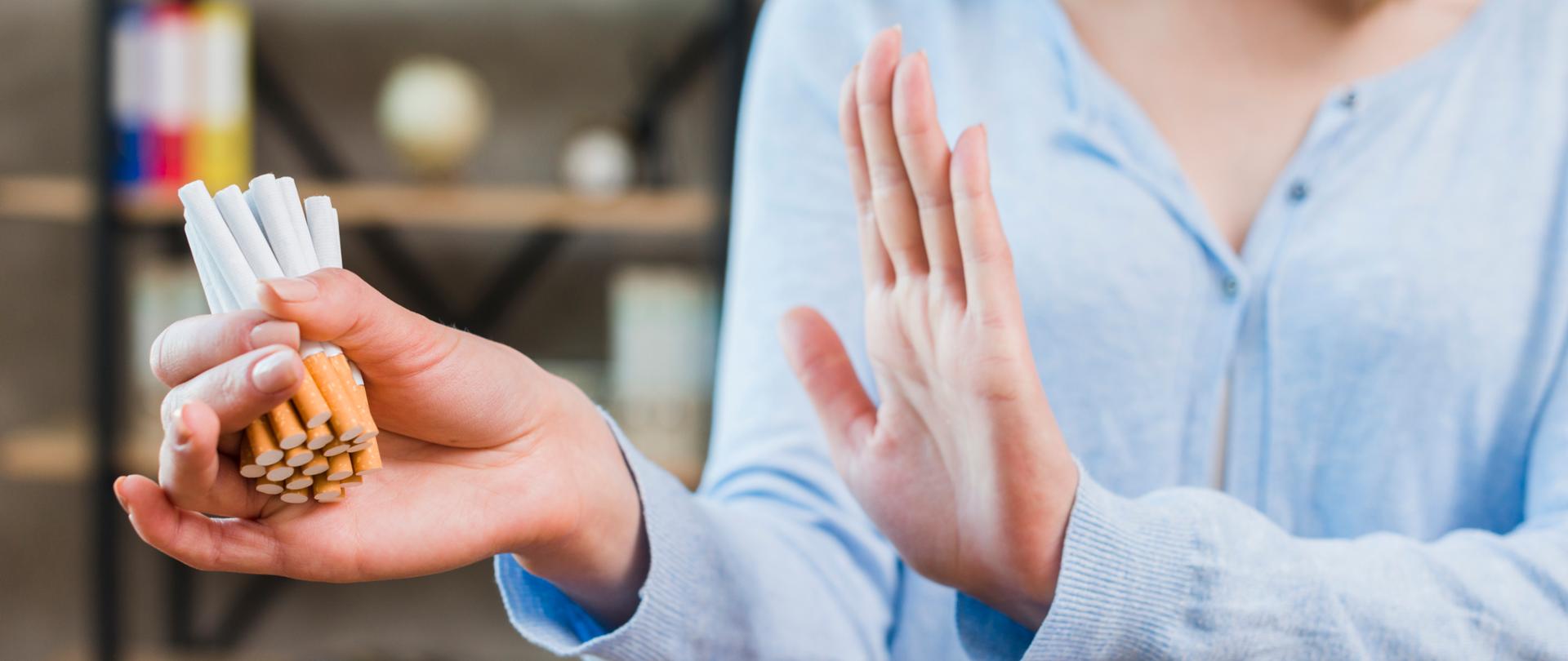 Zdjęcie przedstawia kobietę, która wykonuje stanowczy gest odmowy odnoszący się do zapalenie papierosa.