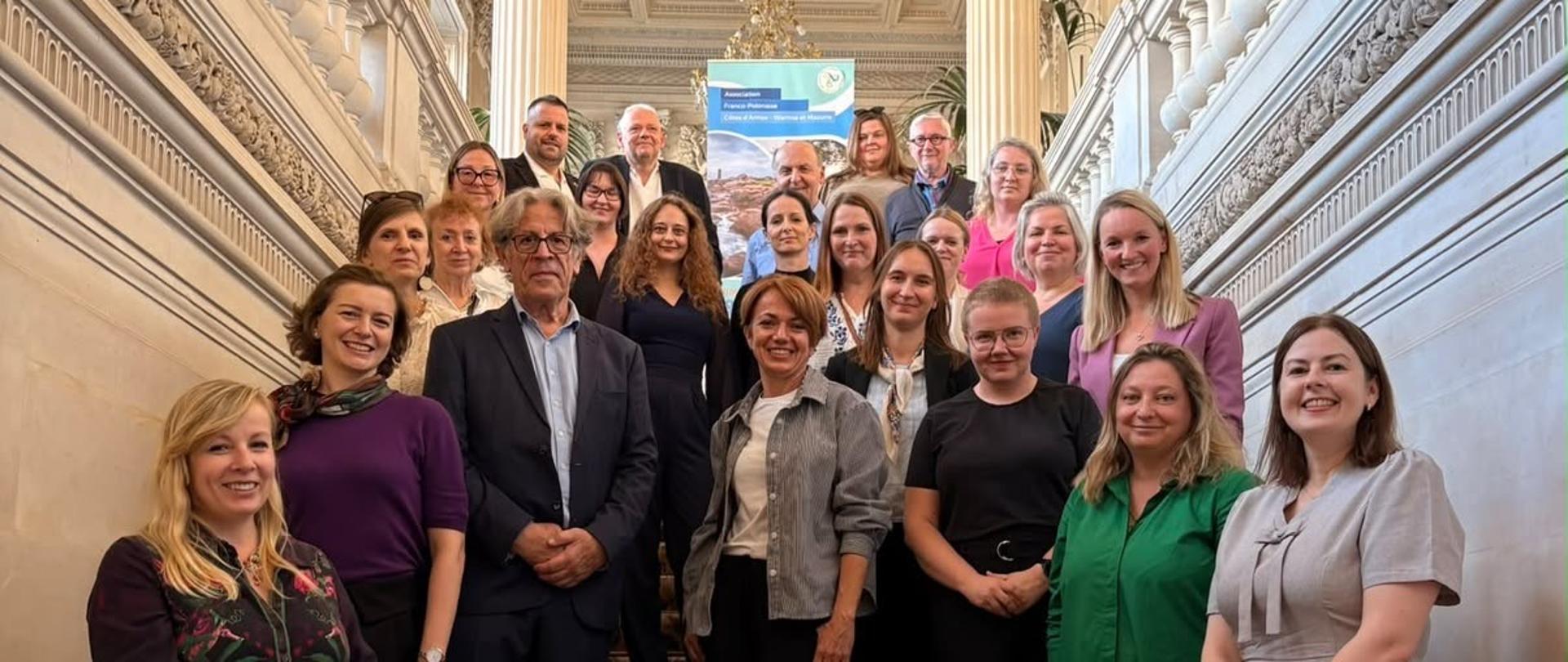Les participants à l'événement posent pour une photo de groupe sur les escaliers.