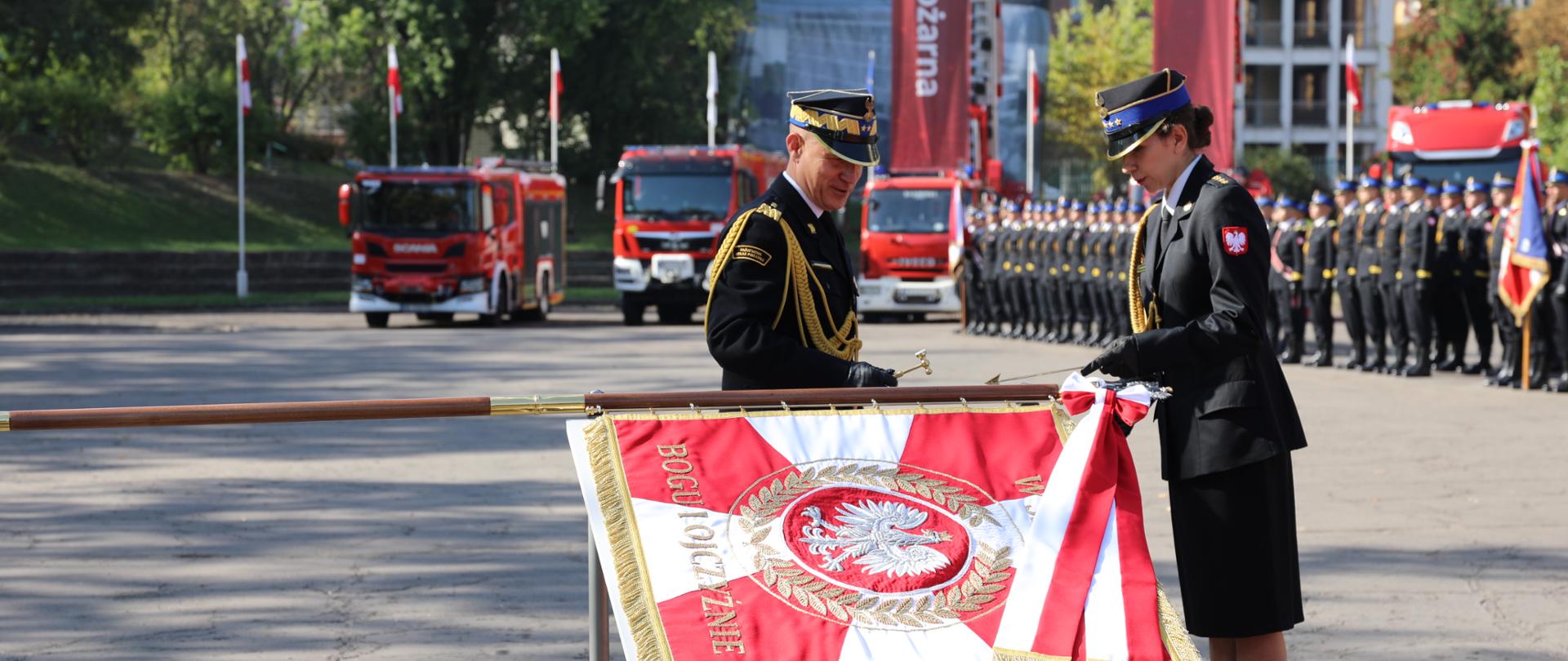 Komendant Główny PSP przybija gwóźdź w drzewiec nowego sztandaru dla Akademii Pożarniczej