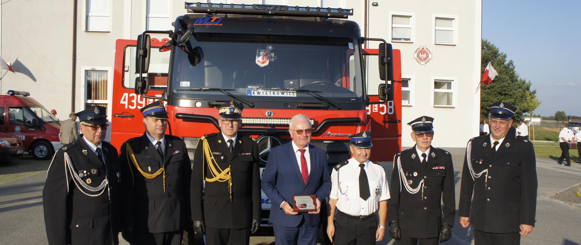 Druh OSP, Komendant Powiatowy PSP w Łasku, Z-ca Komendanta Głównego PSP, Poseł Piotr Polak i trzech druhów OSP ustawieni przed samochodem ratowniczo - gaśniczym 
