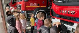 Dzieci oglądają pojazdy pożarnicze w garażu straży pożarnej