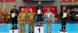 Uczestnicy II Halowych Młodzieżowych Zawodów Sportowo-Pożarniczych pozują na podium z medalami, pucharami i dyplomami po zakończonej rywalizacji.
