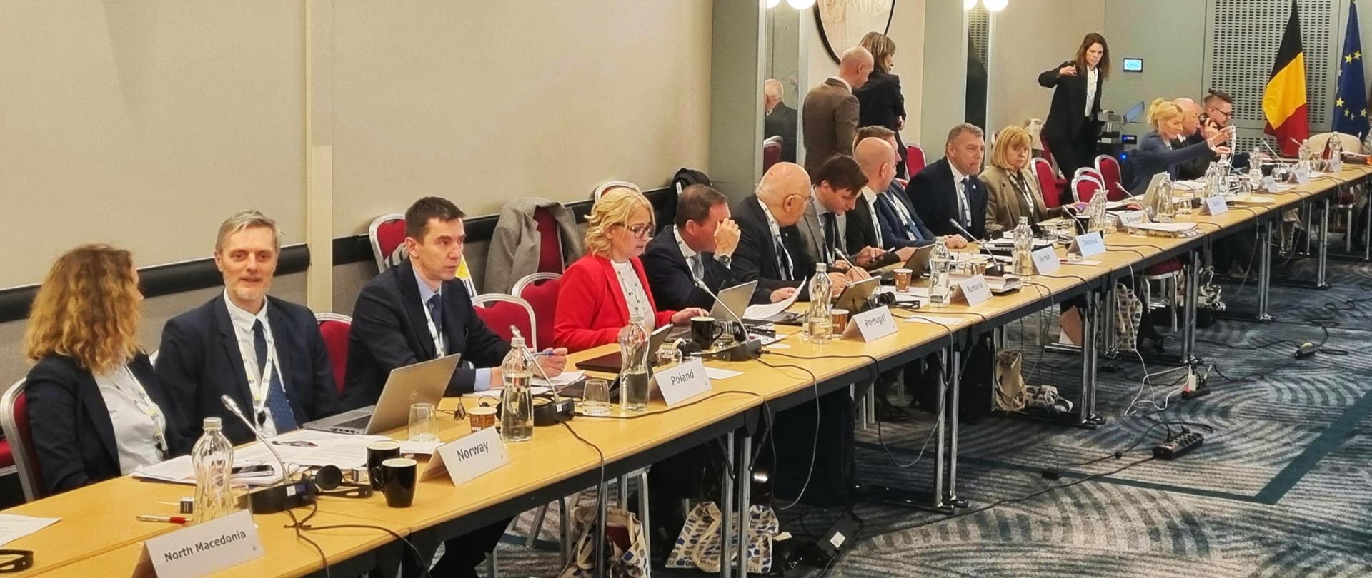 grupa osób uczestniczy w posiedzeniu , wszyscy siedzą przy stole, 