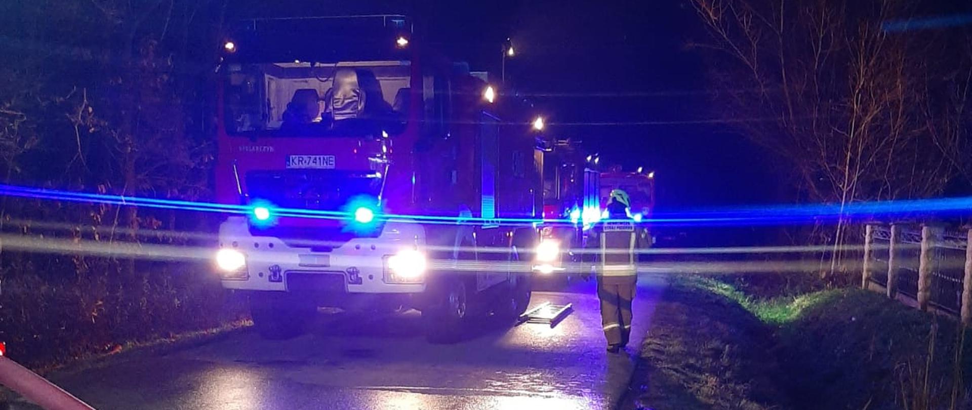 Na zdjęciu widać kolejno ustawione pojazdy gaśnicze, mają włączone światła błyskowe niebieskie.