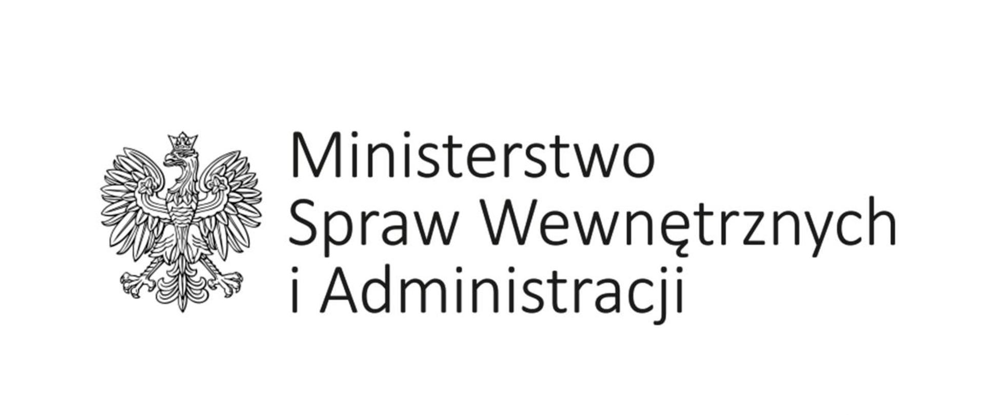Ilustracja przedstawia na białym tle, na środku czarno-biały logotyp Ministerstwa Spraw Wewnętrznych, który składa się z czarno-białego orła oraz napisu Ministerstwo Spraw Wewnętrznych i Administracji. W prawym dolnym rogu napis KW PSP Katowice