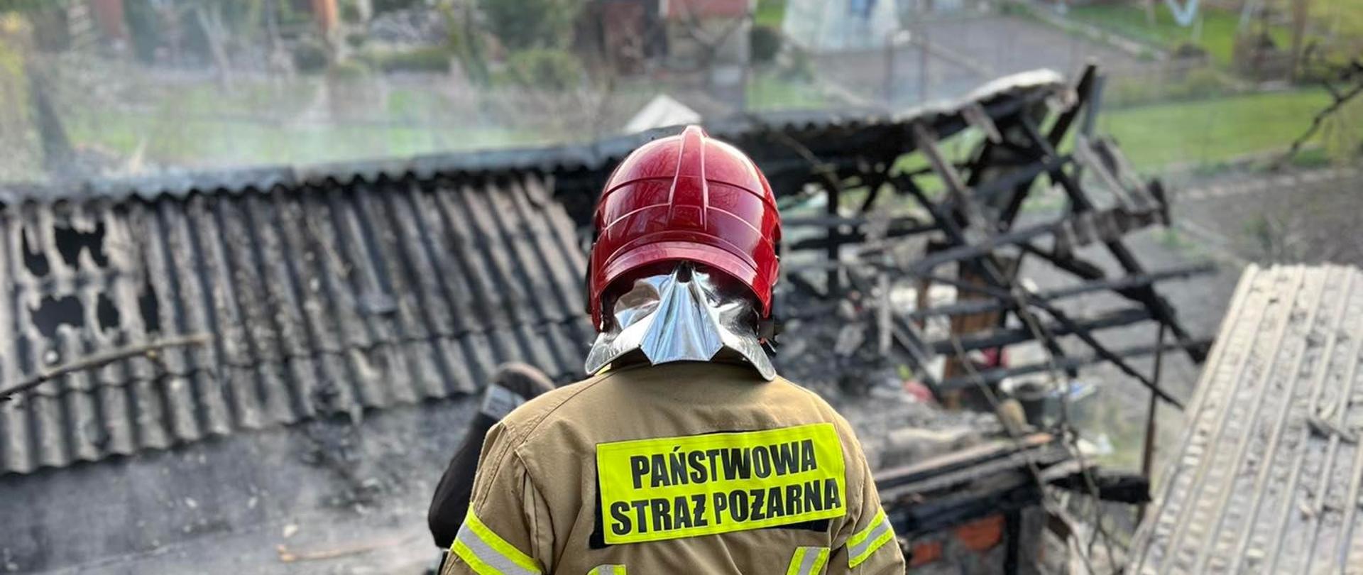 Na zdjęciu widać strażaka i spaloną altanę