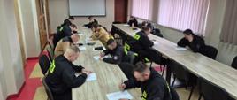 Strażacy OSP siedzą w ławkach i piszą test na świetlicy