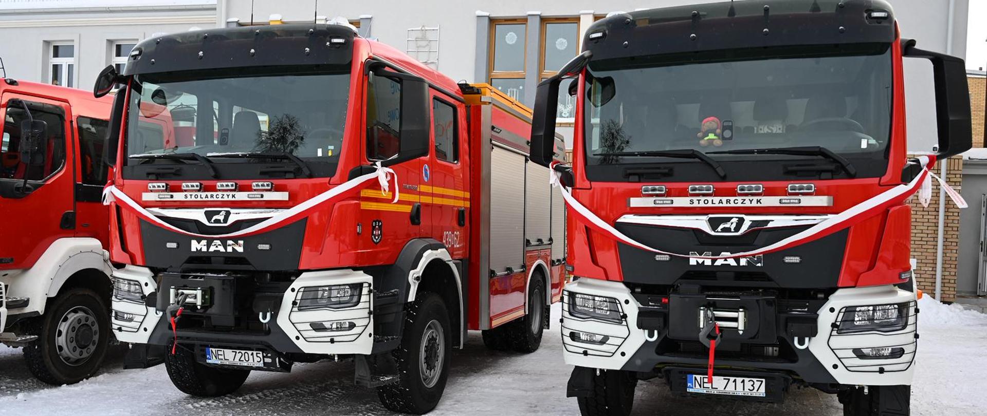 Dwa pojazdy ratowniczo - gaśnicze MAN ze wstążkami czekają na nowych właścicieli
