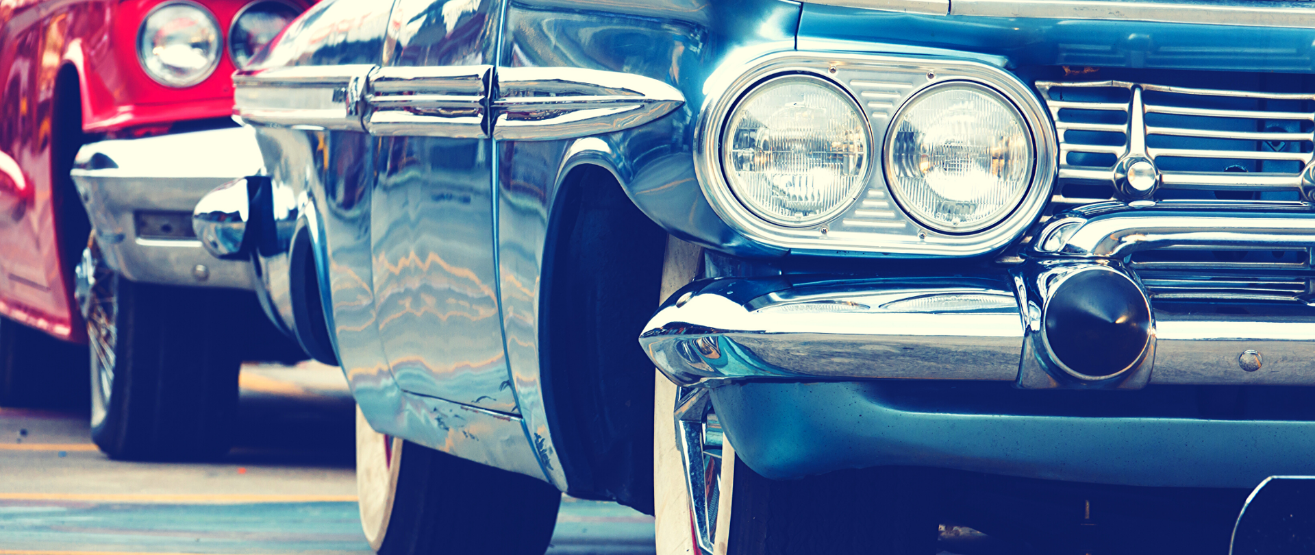 Dwa zabytkowe samochody. Jeden niebieski, drugi czerwony.