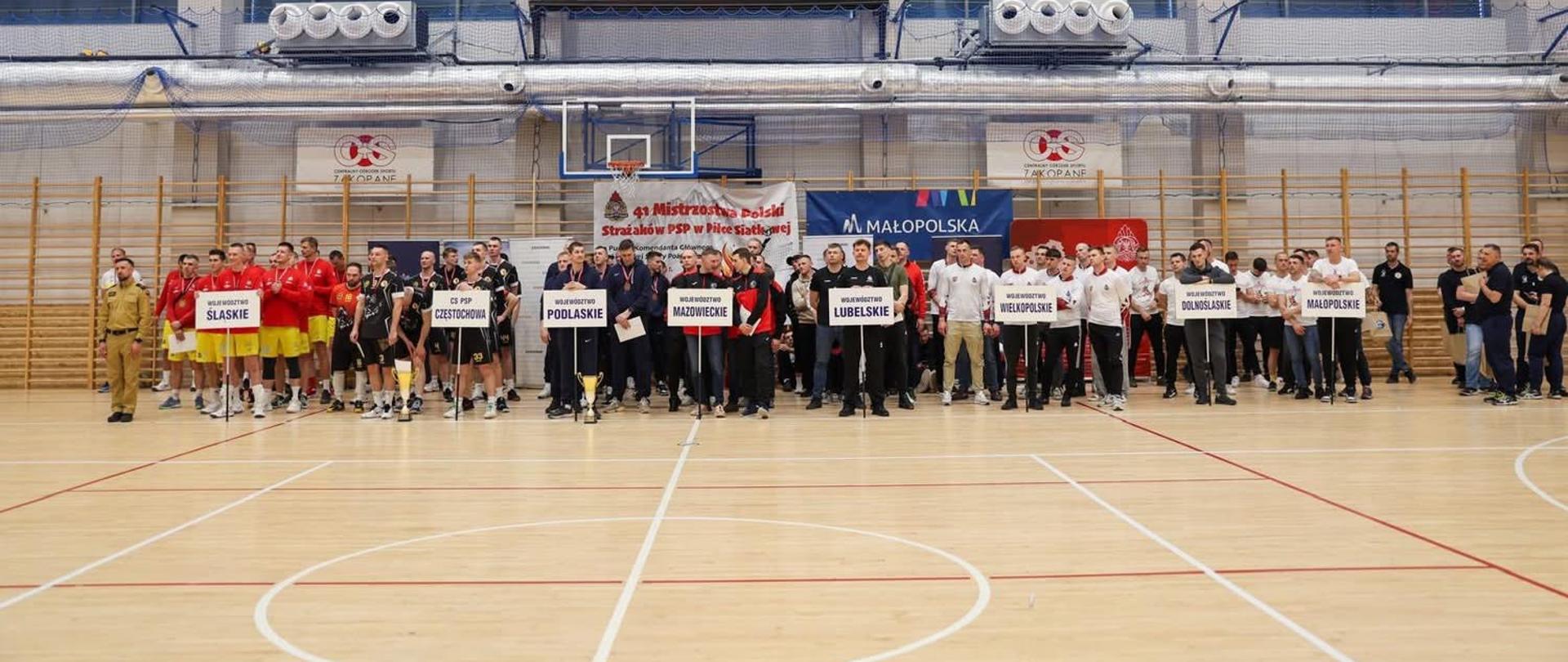 Uczestnicy 41. Mistrzostw Polski Strażaków PSP w Piłce Siatkowej wspólne ustawienie drużyn na hali sportowej w Zakopanem.
