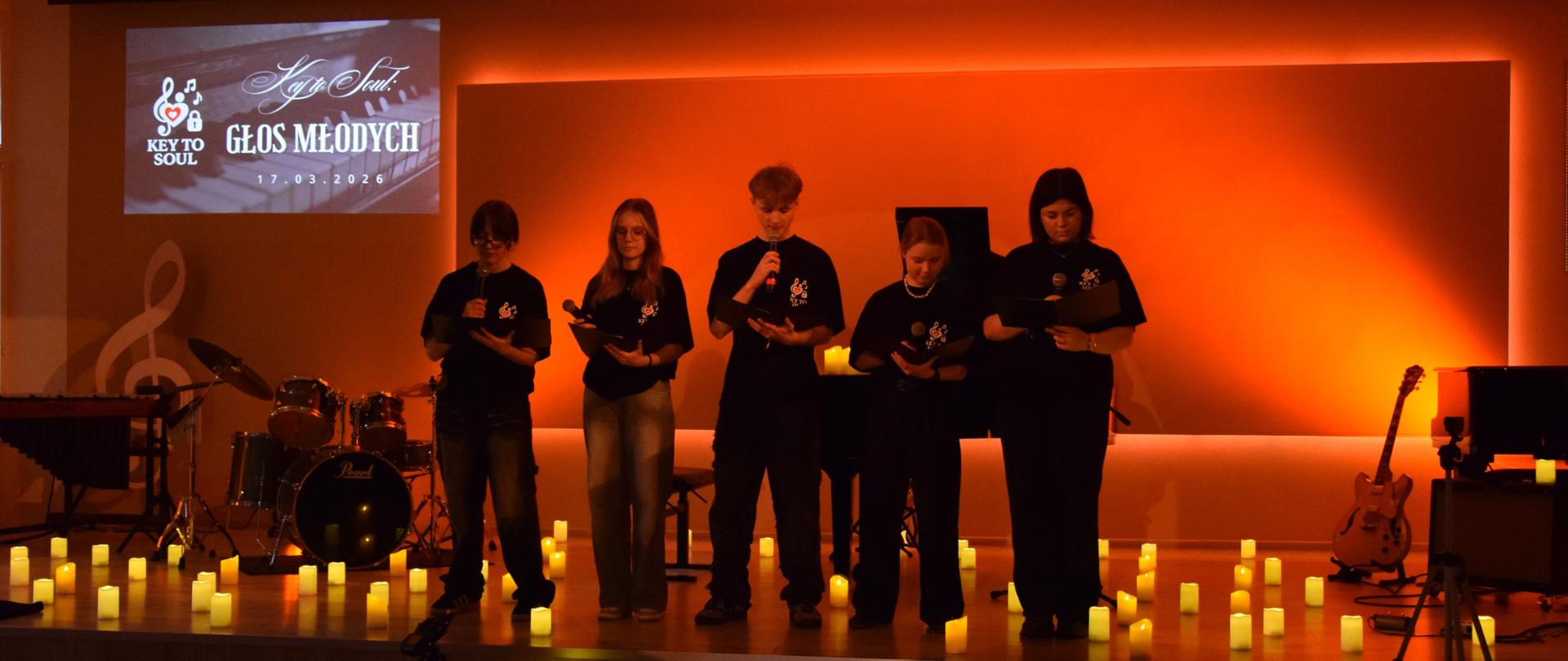 na scenie ze świeczkami zapowiadający uczniowie