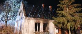 Zdjęcie przedstawia spalony budynek mieszkalny jednorodzinny . Całkowicie spalony dach. 