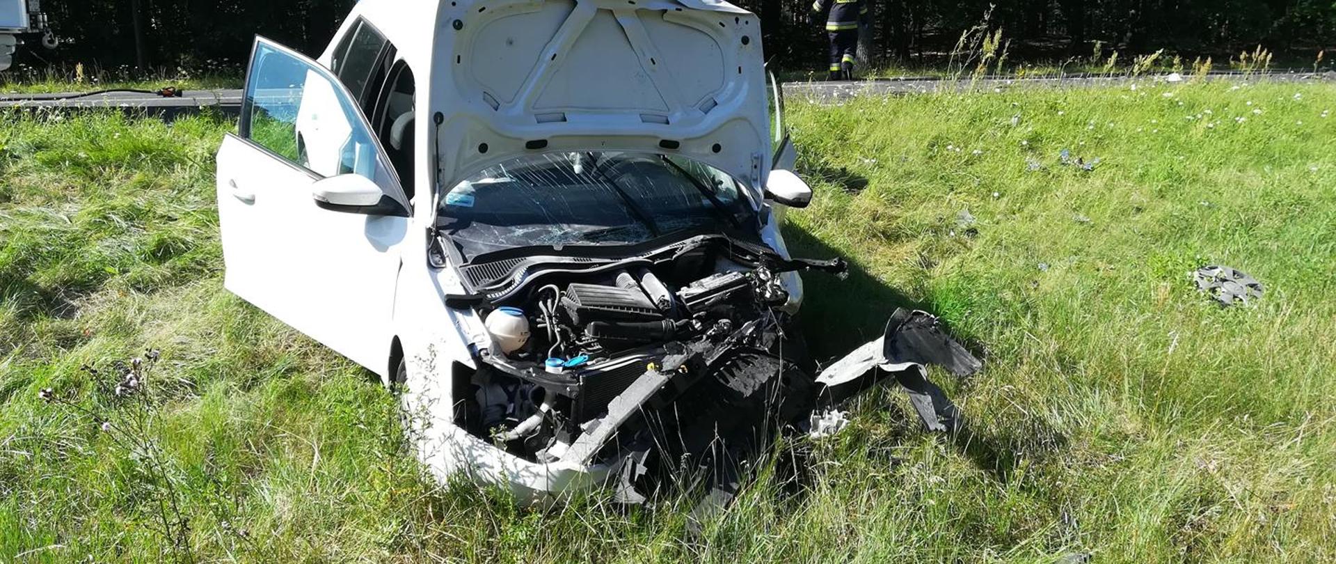 Biały uszkodzony pojazd na poboczu drogi