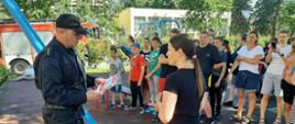 Widoczny strażak PSP wręczający książeczki edukacyjne wychowankom