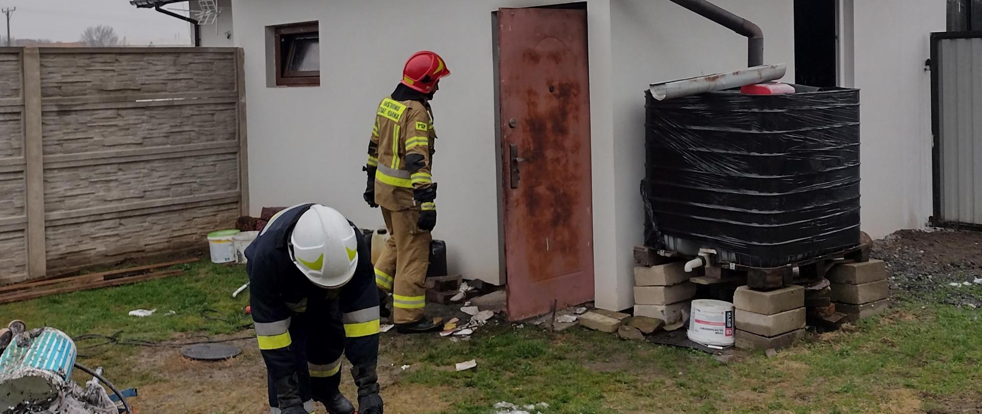 Strażacy przed budynkiem warsztatowym wynoszą nadpalone rzeczy z kotłowni 