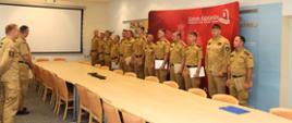 Wnętrze Sali konferencyjnej Szkoły Aspirantów PSP w Krakowie. Mężczyźni, strażacy w umundurowaniu służbowym ustawieniu w szeregu 