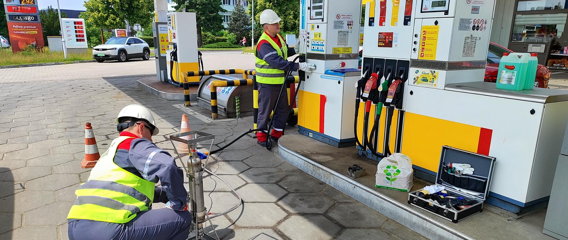 Fotografia prezentująca proces pobierania próbki kontrolnej gazu skroplonego LPG na stacji paliw przez Inspektorów Inspekcji Handlowej