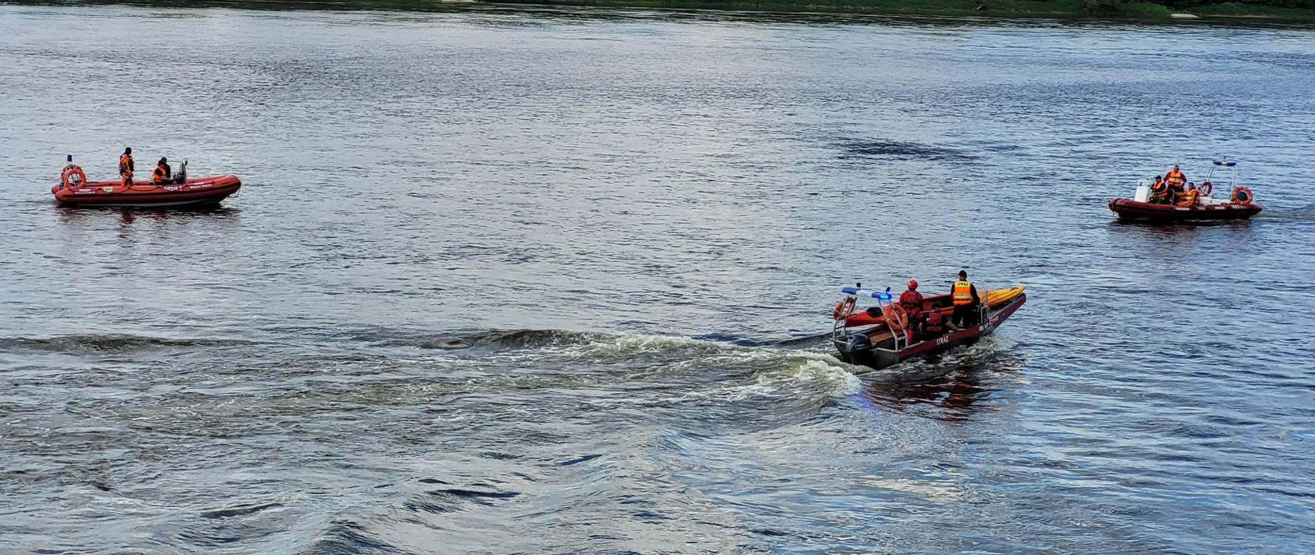 Zdjęcie przedstawia 3 łodzie pływające po rzece. Na ich pokładzie znajdują się strażacy ubrani w sprzęt asekuracyjny.