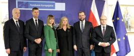 Minister funduszy i polityki regionalnej Grzegorz Puda wraz z uczestnikami konferencji inaugurującej Fundusze Europejskie dla Podlaskiego 2021-2027, minister Puda stoi na tle flag Polski, UE i Podlasia, po jego prawej stronie stoi marszałek województwa podlaskiego Artur Kosicki, drugi od lewej stoi wiceminister edukacji Dariusz Piątkowski 