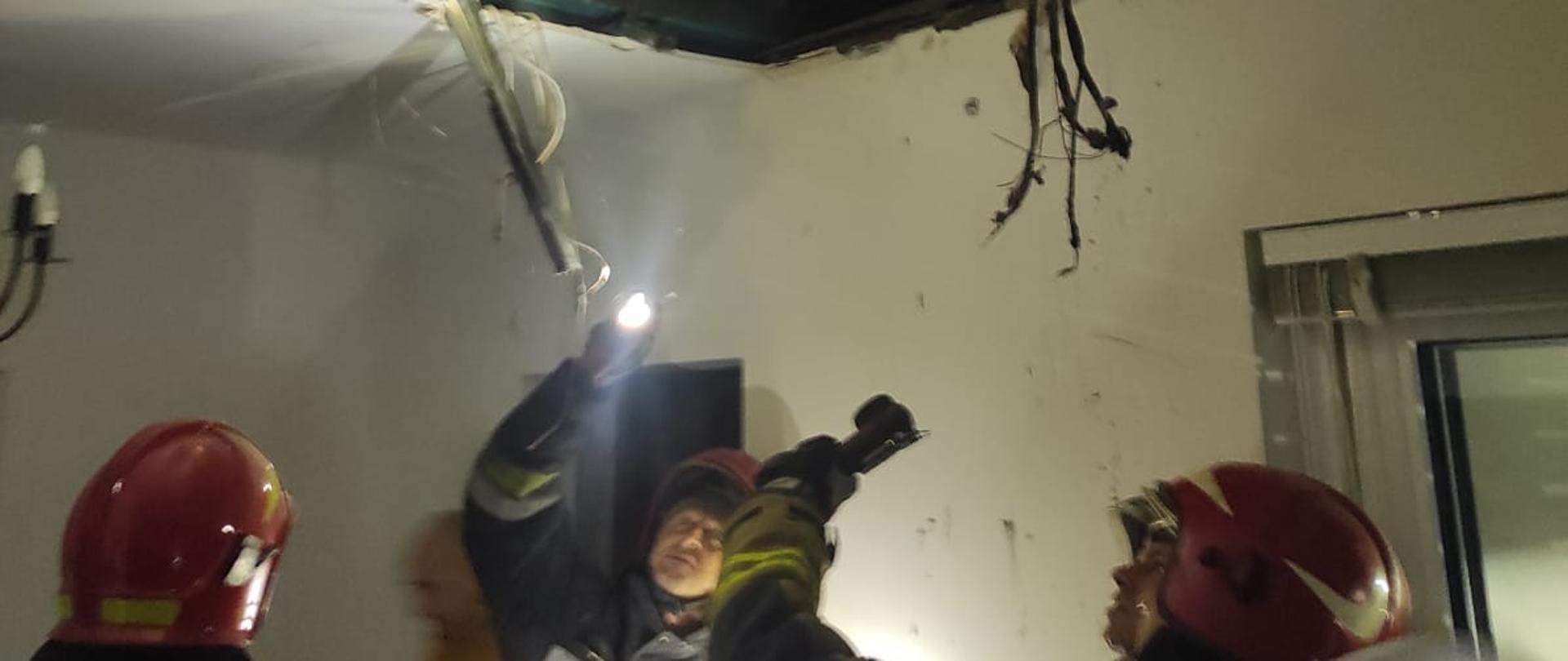 Strażacy pod otworem w stropie.