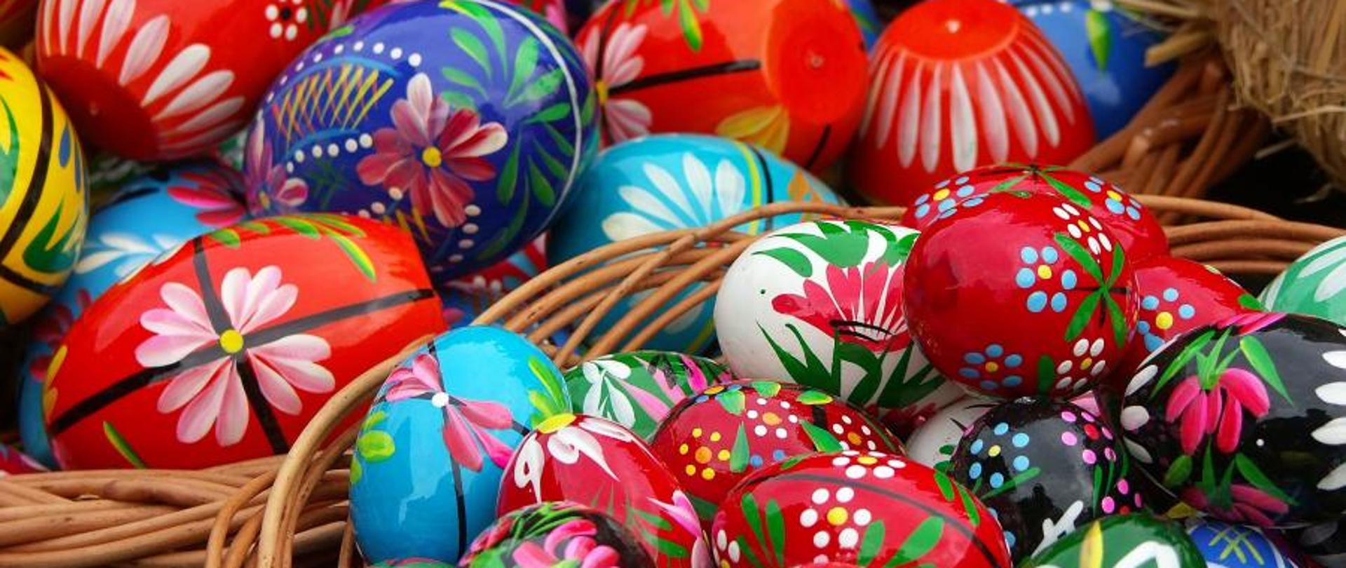 Na zdjęciu widoczne dwa koszyki wiklinowe pełne kolorowych pisanek.