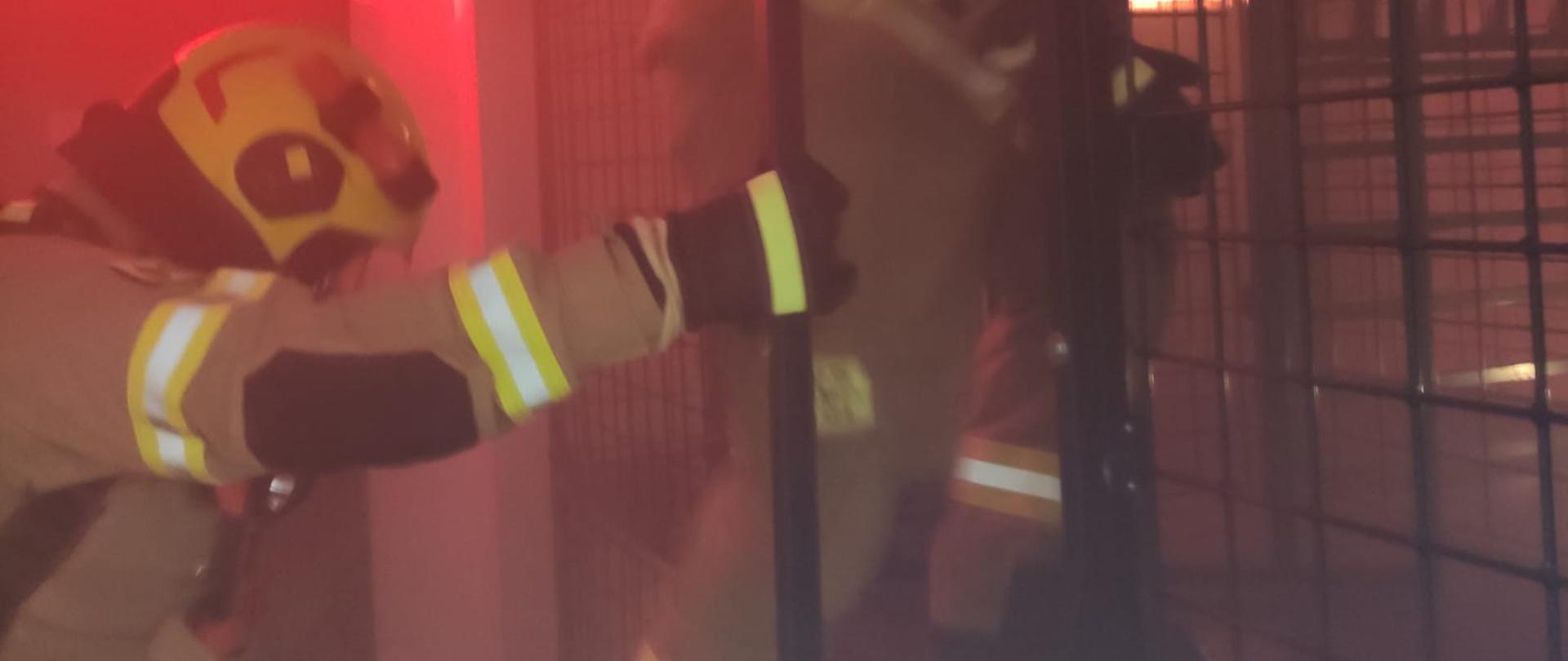 2 strażaków w ubraniu specjalnym z aparatami powietrznymi podczas ćwiczenia w komorze dymowej w Ośrodku Szkolenia. 