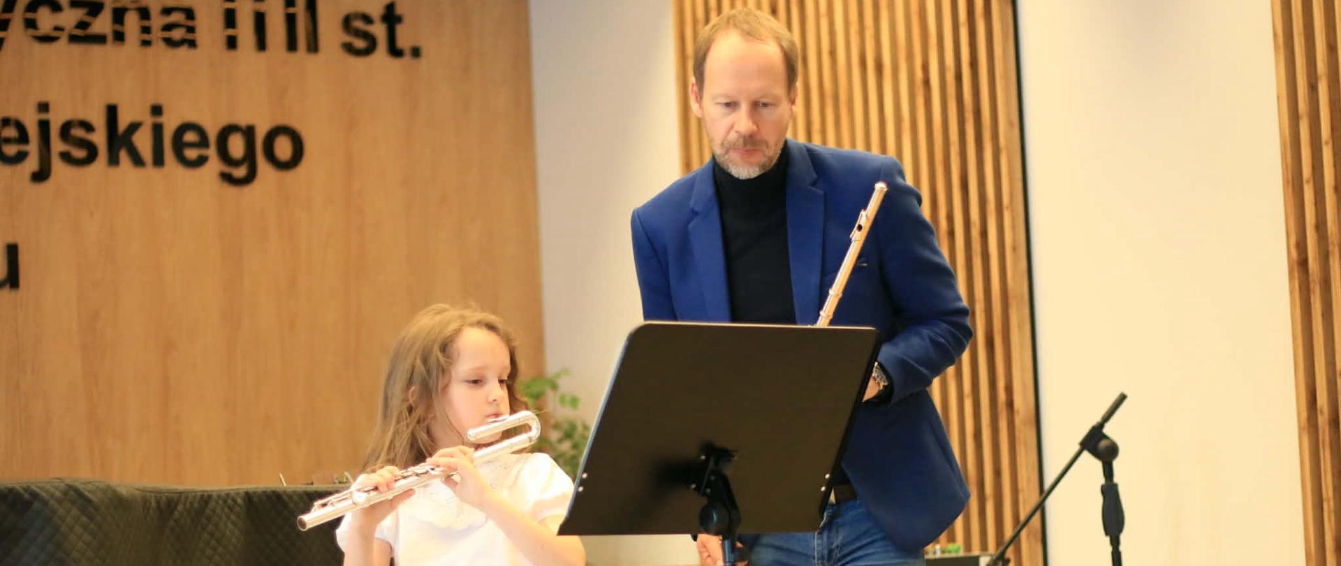 Uczennica z lewej strony z profesorem z prawej strony podczas lekcji warsztatowej.