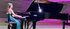 Młoda kobieta gra na fortepianie Fazioli na scenie sali koncertowej PSM w Jastrzębiu-Zdroju