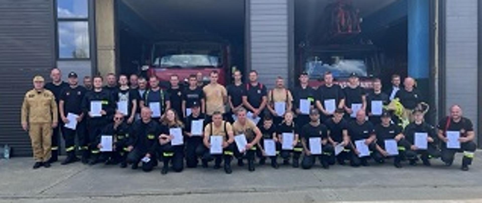 Na zdjęciu pozujący do pamiątkowego zdjęcia strażacy biorący udział w egzaminie końcowym.