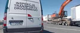 Pojazd inspekcji transportu drogowego, a za nim zespół pojazdów z załadunkiem w postaci koparki podczas przeładunku.