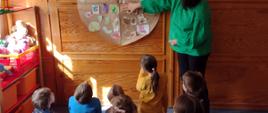 Dzieci przyglądają się swojej pracy – talerzowi zdrowia wiszącemu na ścianie
