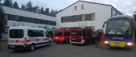 Zdjęcie przedstawia trzy mikrobusy Państwowej Straży Pożarnej oraz jeden autokar czekające na transport uchodźców z Ukrainy