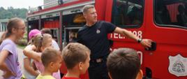 Na zdjęciu strażak oraz wóz strażacki wraz z dziećmi