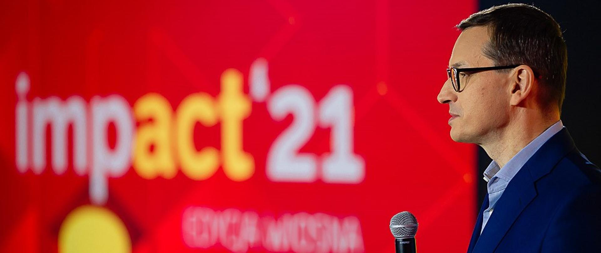 Premier Mateusz Morawiecki stoi podczas wystąpienia.