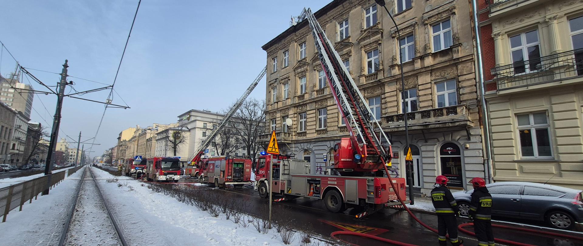 Pojazdy pożarnicze przed kamienicą podczas działań gaśniczych
