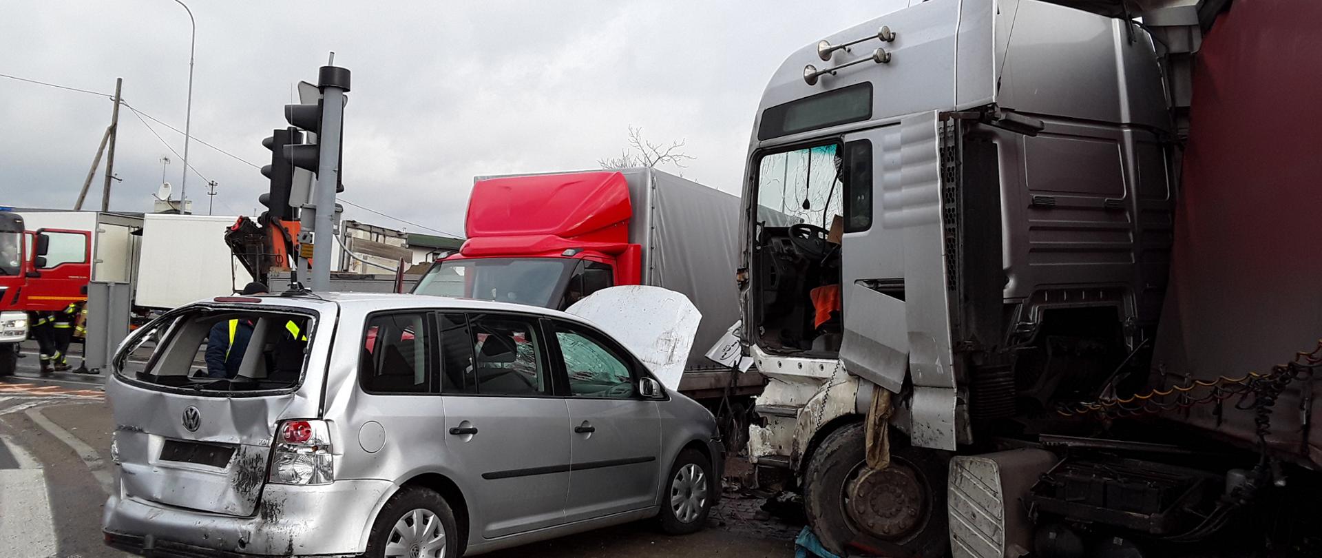 zdjęcie przedstawia Wypadek w m. Rzgów na skrzyżowaniu DK 91 i DK 71. Widoczne uszkodzone samochody osobowy , dostawczy i ciężarowy, w tle stoją samochody straży pożarnej