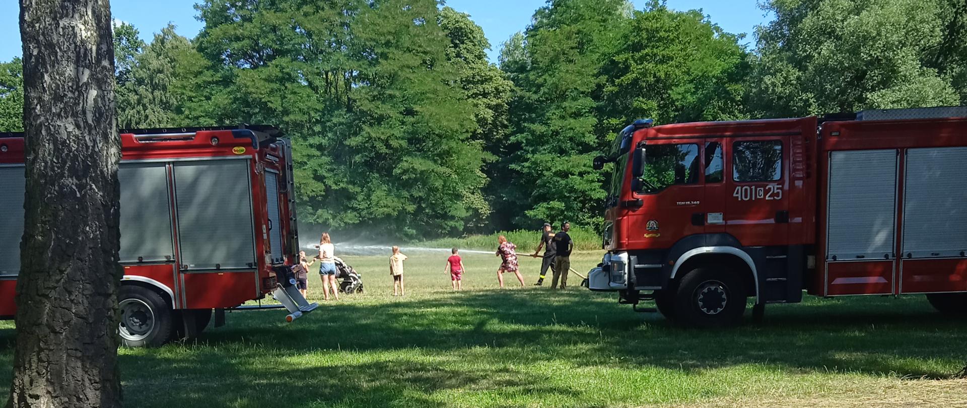 Na zdjęciu widoczny jest średni wóz ratowniczo- gaśniczy z JRG Aleksandrów Kujawski w trakcie prezentacji sprzętu przez strażaków. W kabinie pojazdu i przy pojeździe widoczne są zwiedzające dzieci. W tle widać park