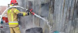Strażak chłodzący zbiorniki wydobyta z pomieszczenia objętego pożarem