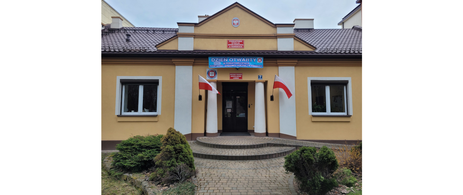 Na zdjęciu widać wejście do siedziby Powiatowej Stacji Sanitarno - Epidemiologicznej w Końskich. Nad wejściem powieszony jest okolicznościowy baner z okazji Dnia Otwartego.