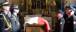 Trumna z nazwiskiem „Sławomir Nocuń” przykryta flagą Polski stoi w centrum świątyni, otoczona szpalerem funkcjonariuszy PSP w czarnych wyjściowych mundurach oraz służby więziennej.