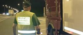 Inspektor lubuskiej ITD stoi obok ciężarówki zatrzymanej do rutynowej kontroli drogowej na autostradzie A2.