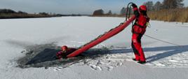 Strażacy w ubraniach do pracy wodzie przeprowadzili ćwiczenia z wykorzystaniem deski lodowej.