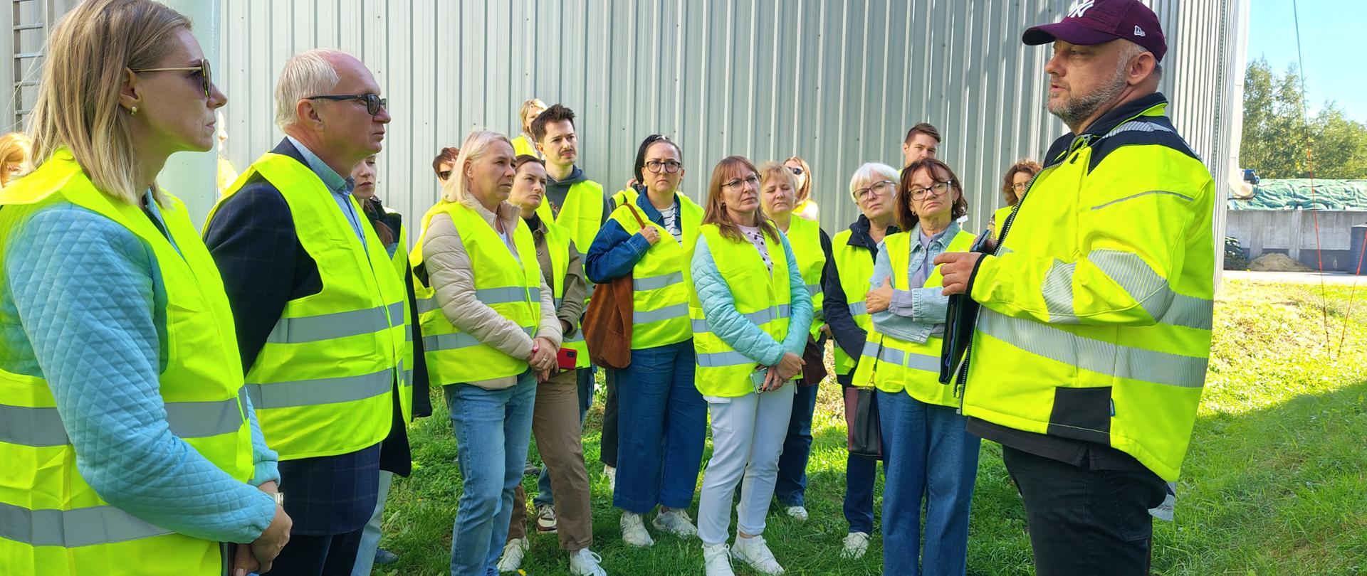 Uczestnicy szkolenia stoją na trawniku i słuchają wykładu. w tle widoczny zbiornik fermentacyjny