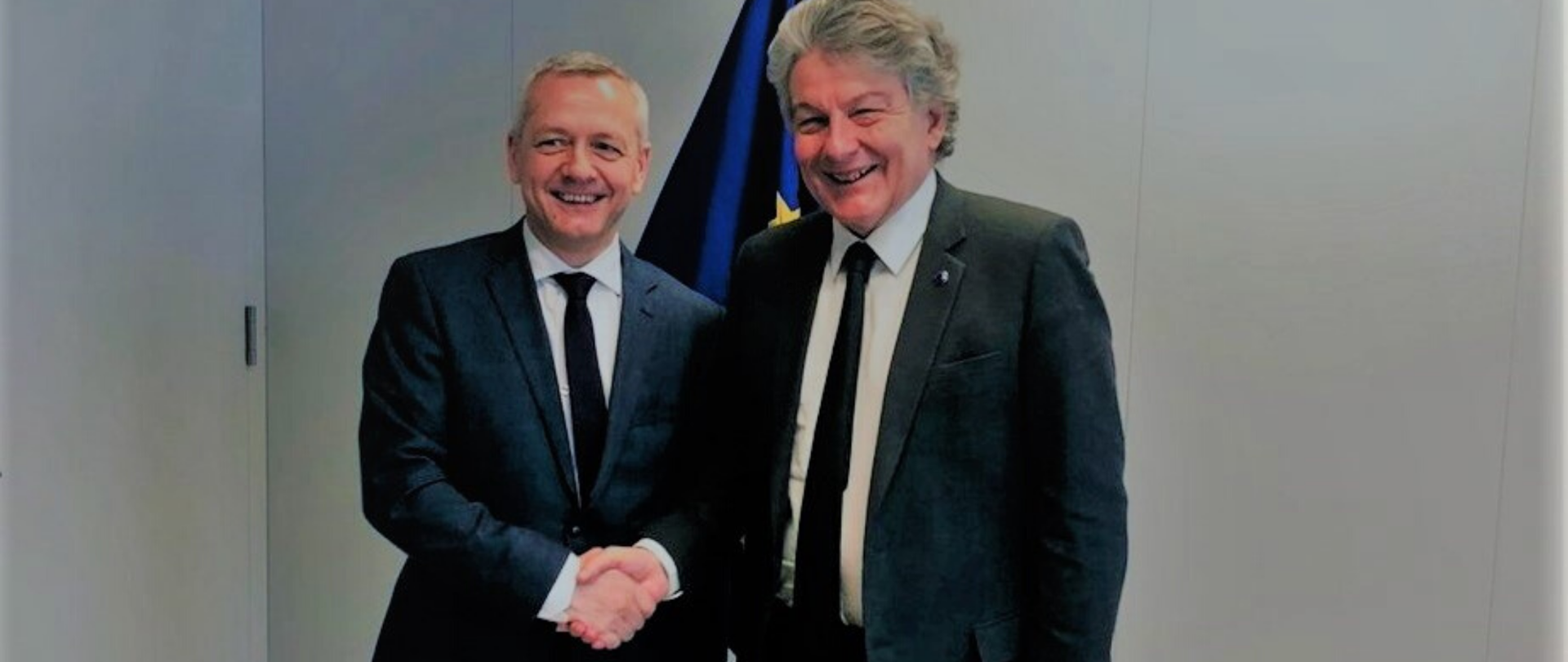 Minister Marek Zagórski and EU Commissioner Thierry Breton pose for a photo shaking hands against the background of the EU flag