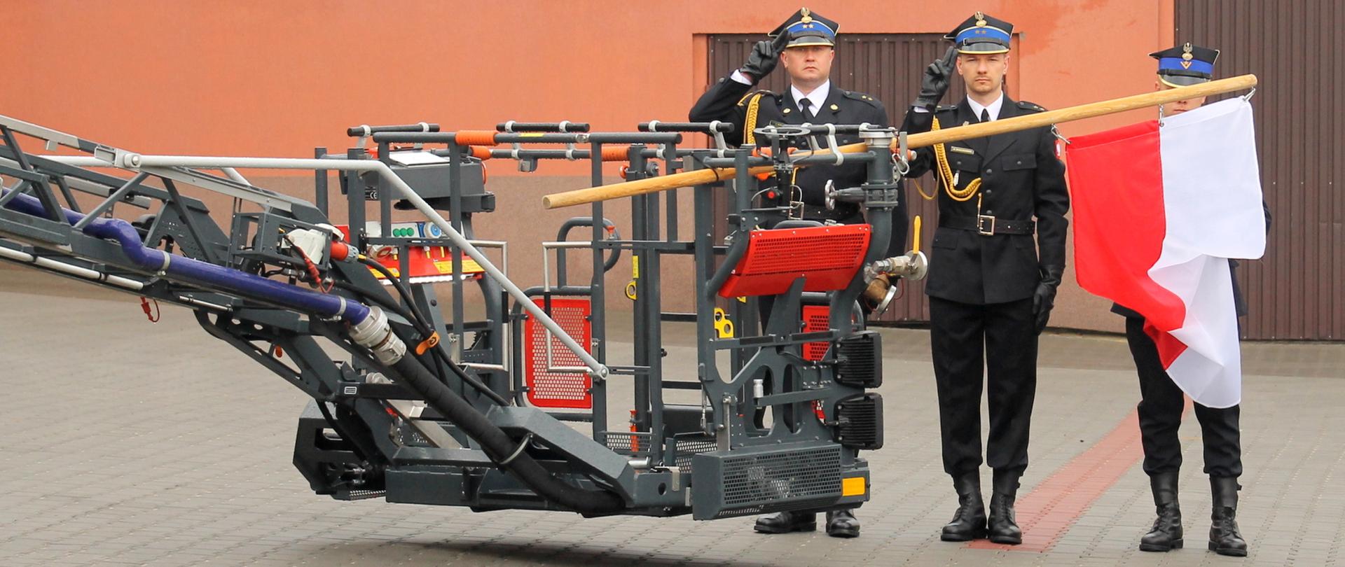 Zdjęcie przedstawia poczet flagowy podczas podnoszenia Flagi Państwowej na drabinie mechanicznej. 