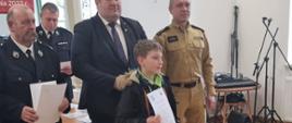 Zdjęcie przedstawia uczestnika turnieju OTWP oraz strażaków i wójta którzy wręczają dyplomy