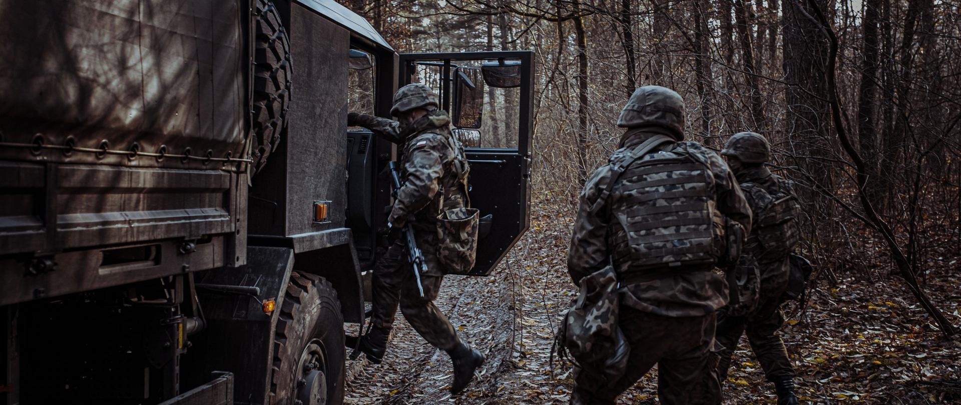 Leśna droga. Żołnierze wsiadają do samochodu wojskowego.