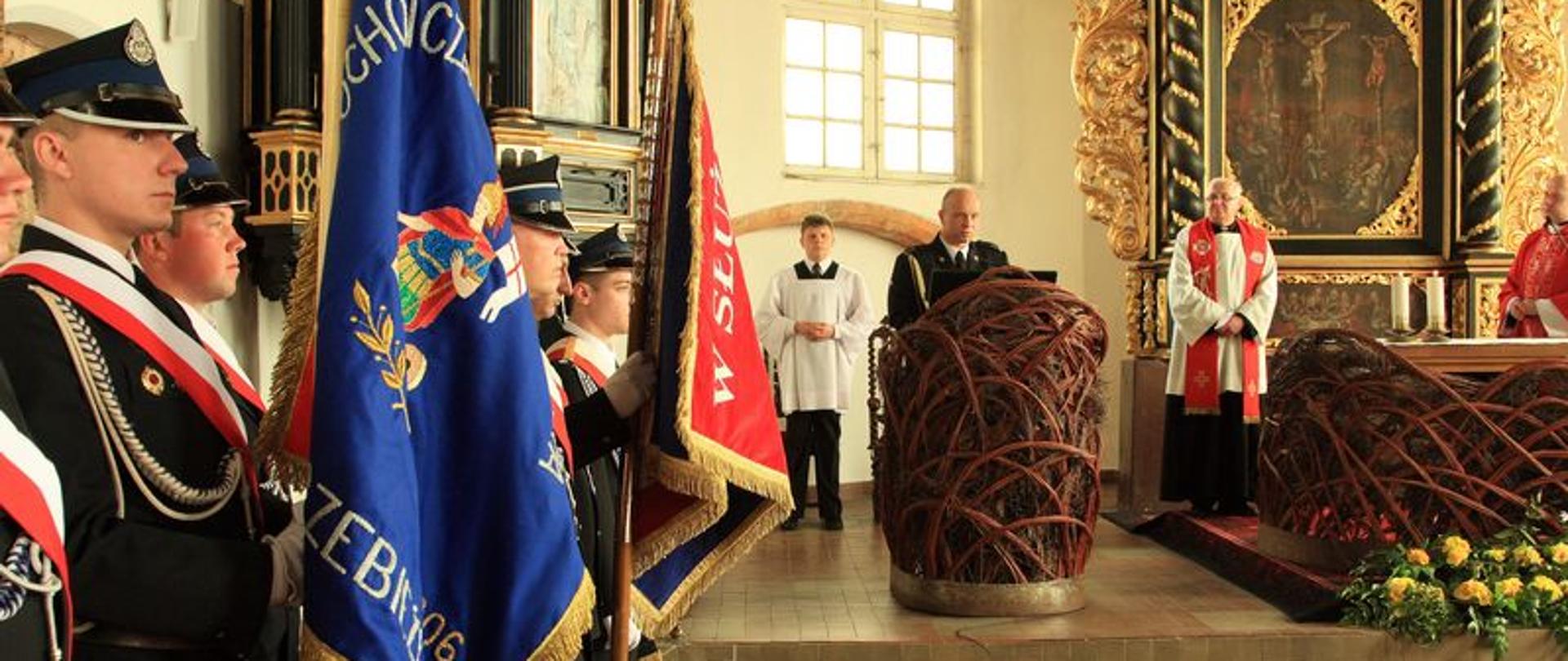 Zdjęcie przedstawia poczty flagowe w kościele na tle ołtarza