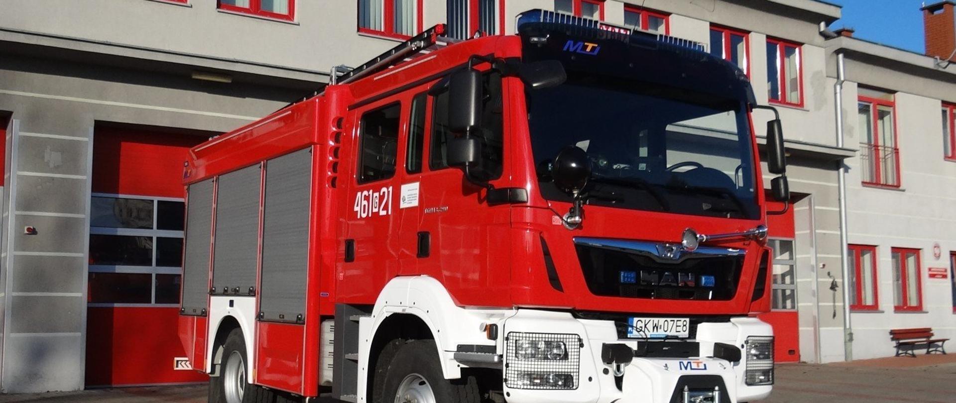 Na tle budynków JRG widać samochód pożarniczy.