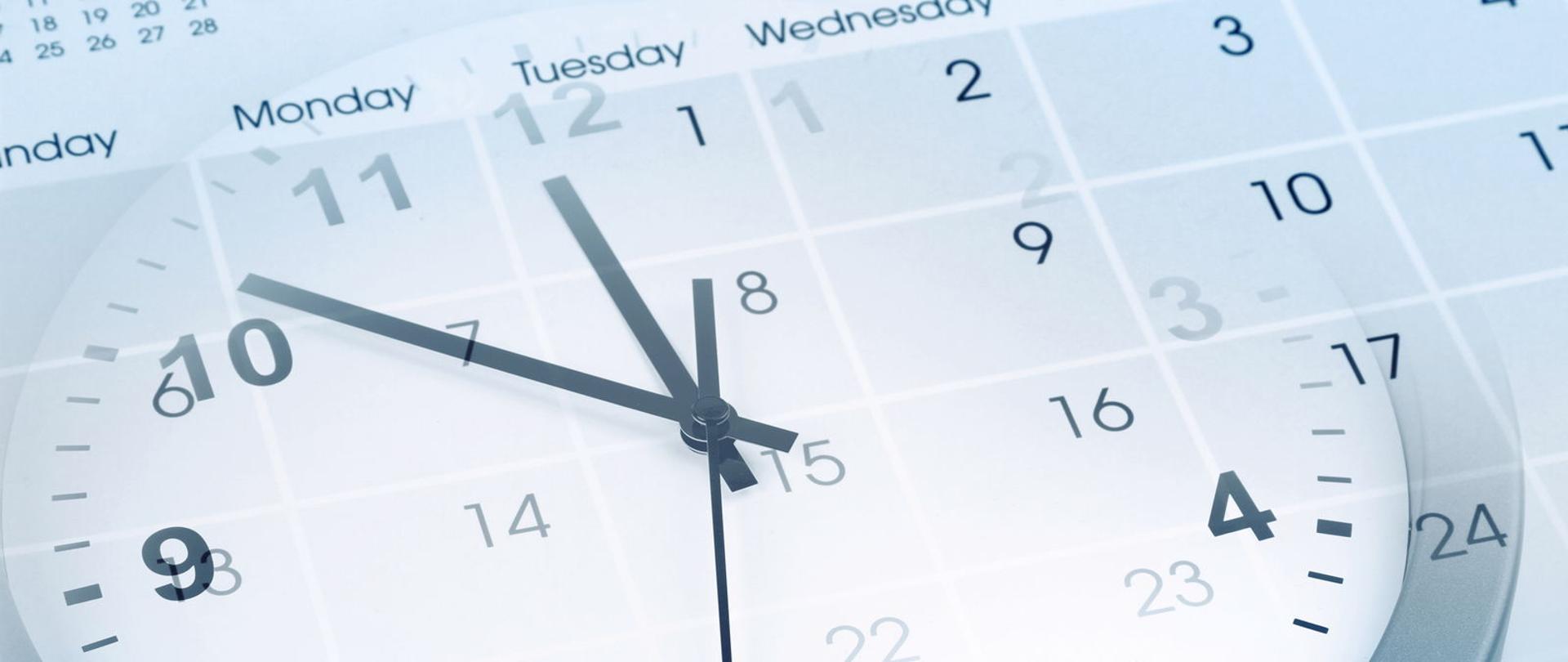 Zegar ze wskazówkami, na tle białego kalendarza.